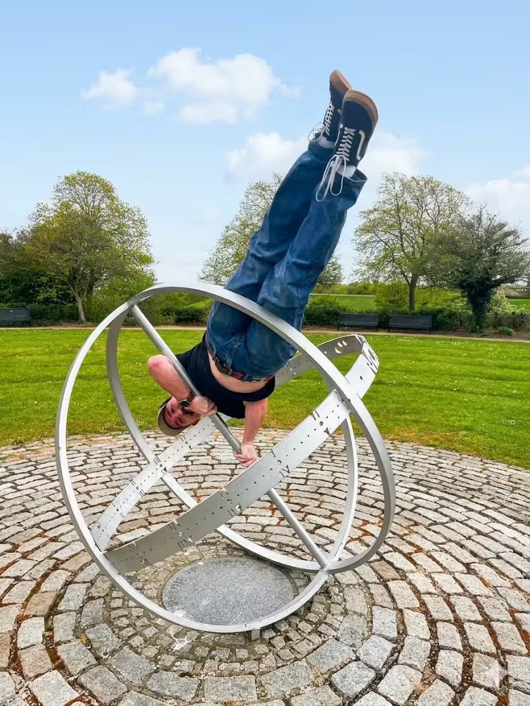 An adventurous participant performing a handstand inside a large metal globe sculpture.