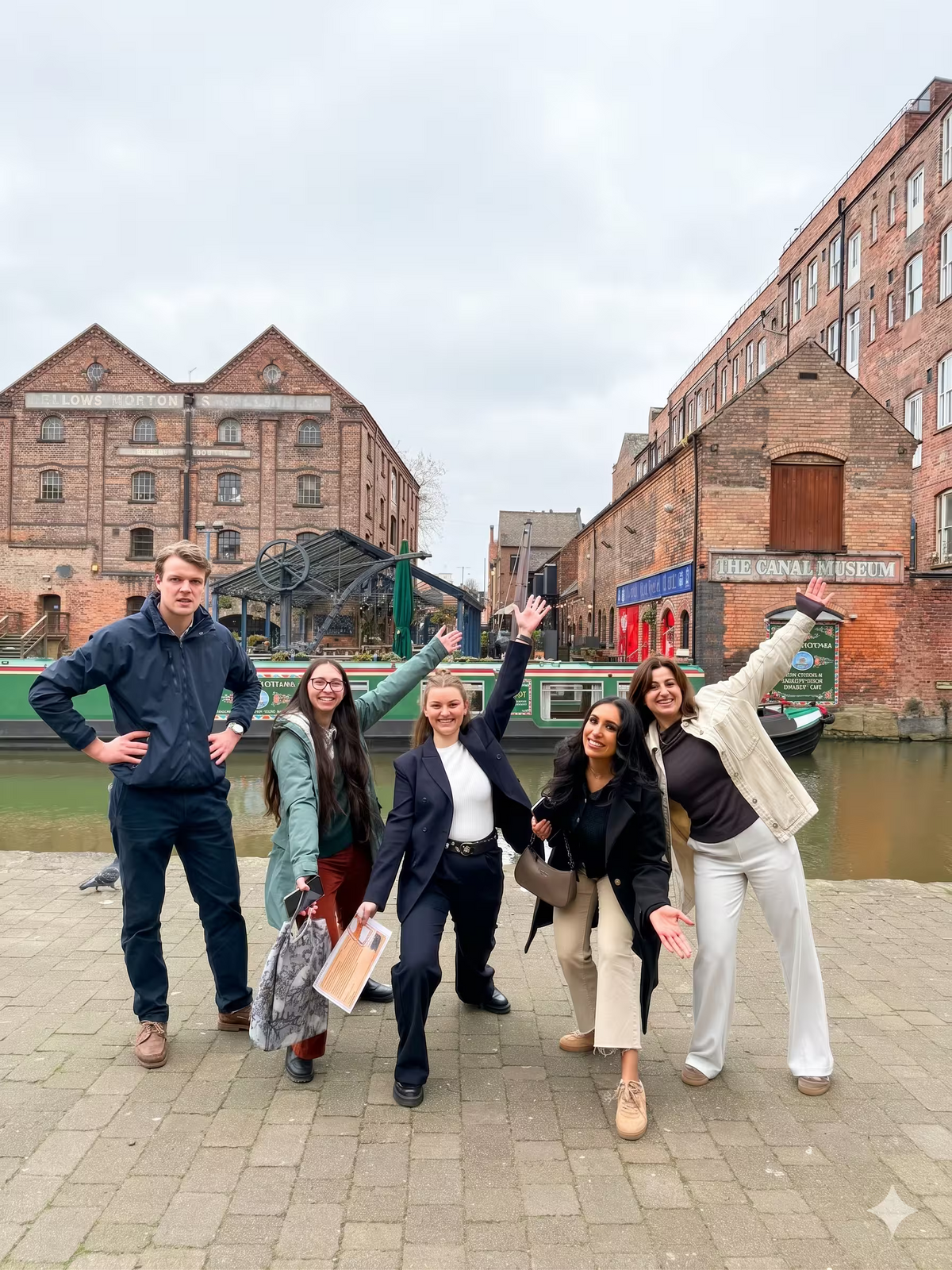 A group of coworkers posing together in front of a historic dockyard and brick buildings.