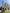 A small team of three people forming a human pyramid on a grassy lawn in front of a historic stone cathedral during a city scavenger hunt.