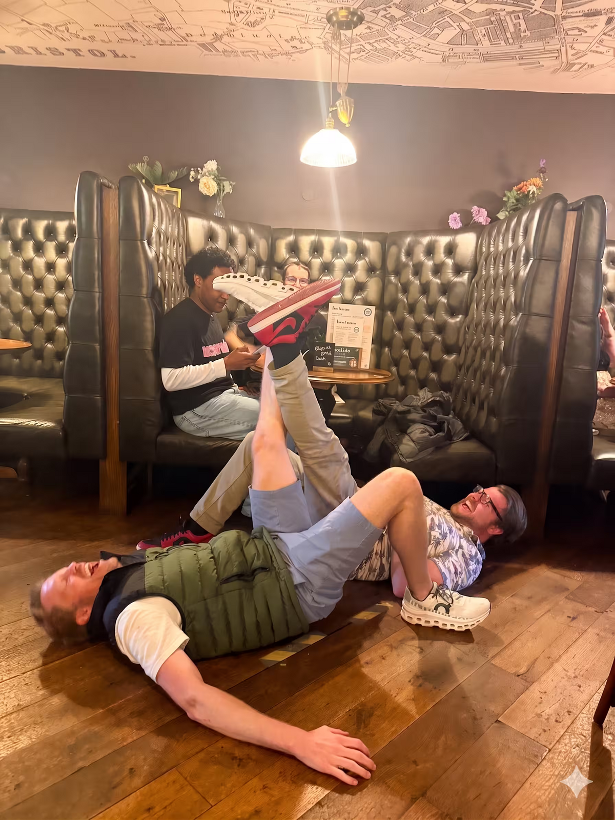 A humorous photo of teammates lying on the floor in a pub as part of a creative task.
