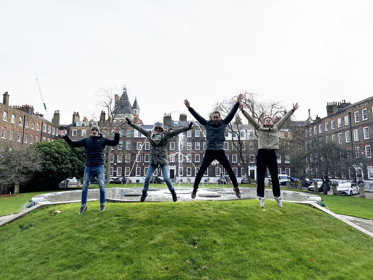Four team members jumping in sync in a city park for an outdoor photo challenge.