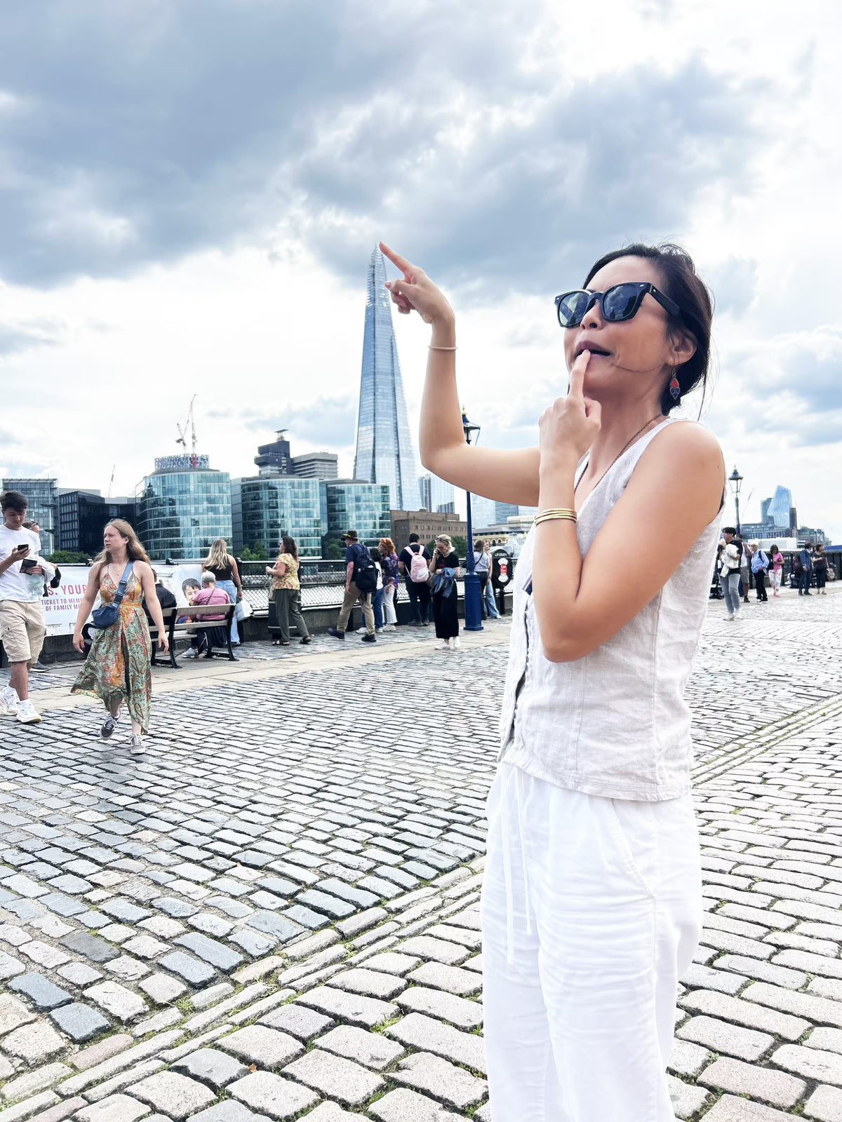 A woman using forced perspective to "touch" a skyscraper in the distance.