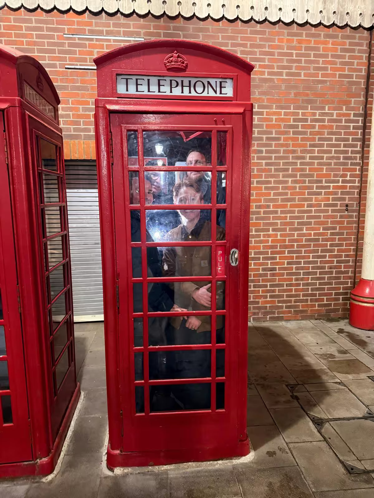 Multiple people squeezed into a classic red British telephone booth for a photo task.