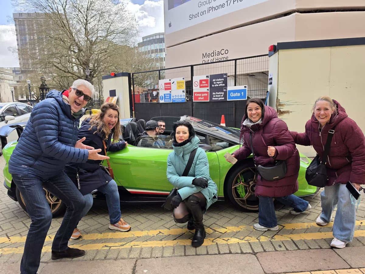 Participants posing with a bright green luxury sports car on a city street.