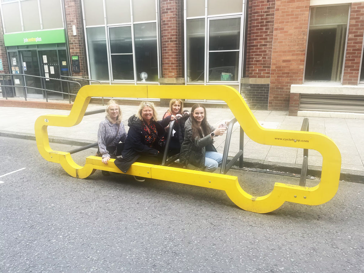 A team sitting on a unique yellow car-shaped bench for a scavenger hunt photo.